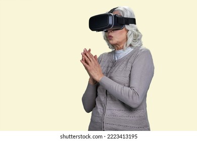 Old Woman With Virtual Reality Headset Is Stunned By VR Experience. Isolated On Yellow.