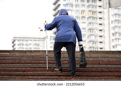 Old woman with walking cane climbing stairs on city street. Concept for disability, limping adult, diseases of the spine - Powered by Shutterstock