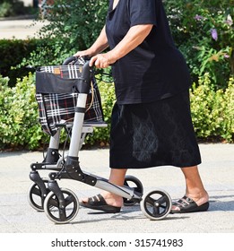 Old Woman Walks On The Street With A Walker