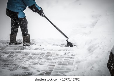 Old Woman In Warm Blue Jacket Clears A Snowdrifts With A Snow Shovel. Toned.