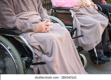 Old Woman In The Wheel Chair. Close-up Shot Of Her Hands.