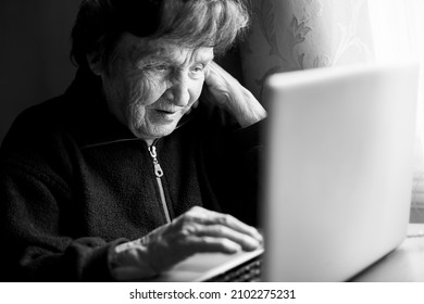 Old Woman Working On The Computer In Her Home. Black And White Photo. 