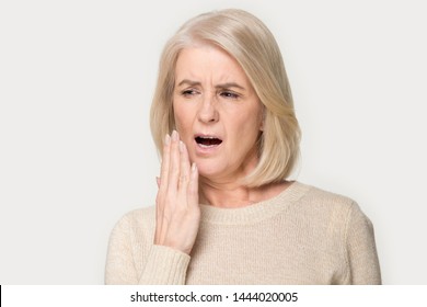 Old woman yawn cover mouth with hand being bored. Elderly female feeling exhausted, sleepy, tired, overworked, no energy headshot. Lady in years gaping portrait at studio isolated on grey background - Powered by Shutterstock