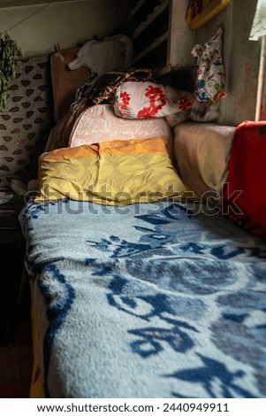 An old woman's bed in a traditional village house. Blanket and pillow. traditional patterns. old stuff. misery. living in poor conditions.