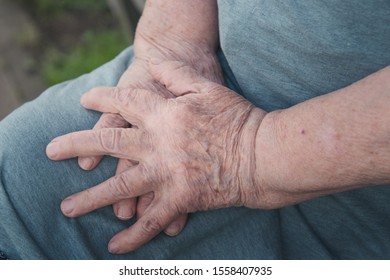 old woman's hands on her knee - Shutterstock ID 1558407935