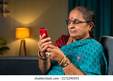 Old Women Using Basic Keypad Mobile Phone While At Home - Concept Of Technology, Old Fashioned And Relaxation