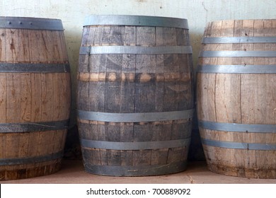 Old Wood Barrels Lining A Worn Weathered Wall In The Basement Of An Old Building. Used For Food Storage In Early American History