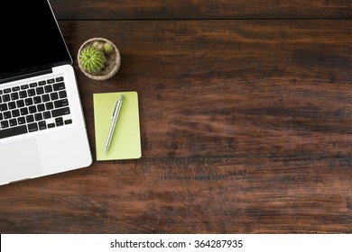 Old Wood Office Desk Table With Laptop, Green Notebook And Pen. Top View With Copy Space.