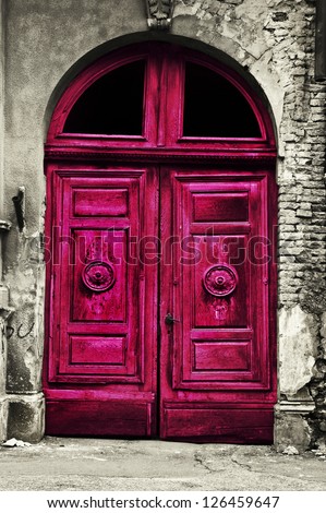 Old wood red door with damaged brick wall