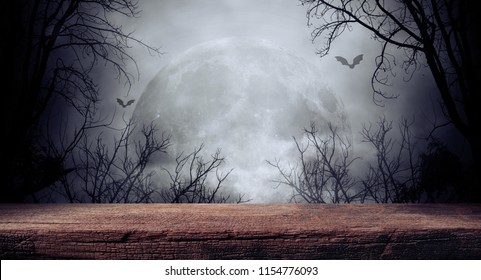 Old wood table and silhouette dead tree at night for Halloween background. - Shutterstock ID 1154776093