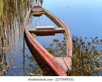 Old wooden abandoned boat canoe in calm lake water with reed grass. - Powered by Shutterstock