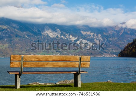 Old wooden bench near the coast of a mountain lake.