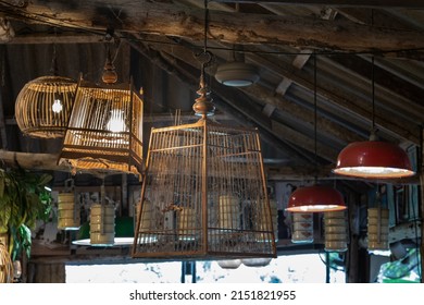 Old wooden birdcage hanging from a wooden beamed ceiling to decorate the interior of country-style pub or restaurant. Vintage birdcage, Antique birdcage, Selective focus.
