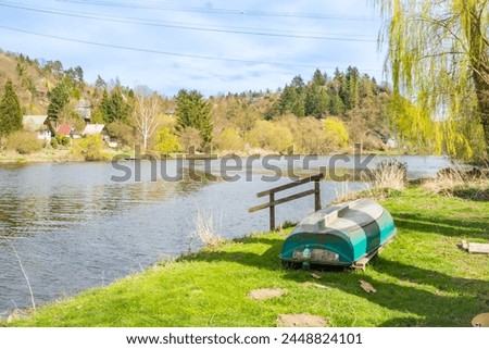 An old wooden boat on the shore. A small fishing boat lies upside down. Czech