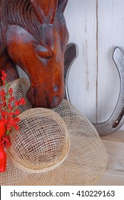 An Old, Wooden Bookend Of A Horse's Head With A Straw Hat And A Horse Shoe On Wooden Background. Great For Kentucky Derby Or Any Horse Race