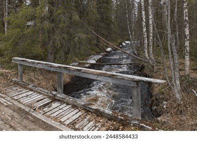 Old wooden bridge over Raakunjoki river in cloudy spring weather at Riutukka Log Floating Museum, Salla, Lapland, Finland. - Powered by Shutterstock