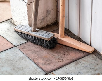 An old wooden brush and mop are standing in the corner. - Shutterstock ID 1708554862