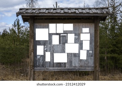 Old wooden bulletin board outdoors with empty white notes.