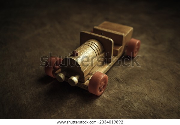 An old wooden car with red wheels on a\
wooden table. A children\'s toy in a retro\
style.