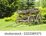 An old wooden cart with large wheels in the farm with forest background