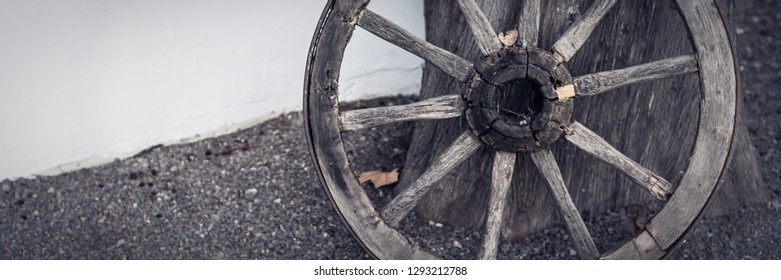 An Old Wooden Cartwheel Stands At The Wall Of The House