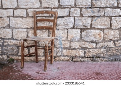 Old wooden chair in front of stone wall 