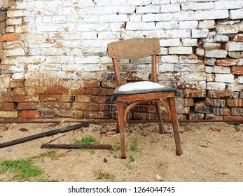 old wooden chair standing near the brick wall of a ruined house