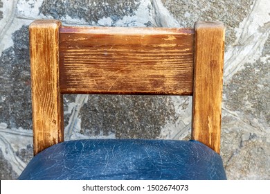 An Old Wooden Chair With A Torn Leather Seat.