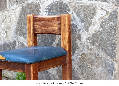 An Old Wooden Chair With A Torn Leather Seat.