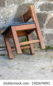 An Old Wooden Chair With A Torn Leather Seat.