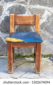 An Old Wooden Chair With A Torn Leather Seat.