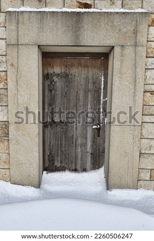 Old wooden church door with snow under it