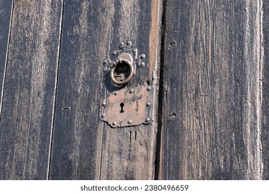 Old wooden church door with vintage lock. Wooden door covered in tar. Locked historical church entrance with old locking system