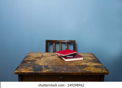 Old wooden desk and chair with books and a pen