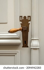 An Old Wooden Door With A Brass Doorknob.