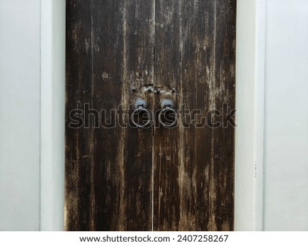 Old wooden door, flanked by white concrete walls, looks simple.