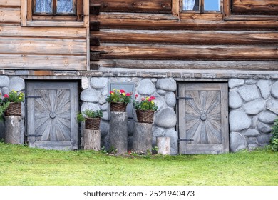 old wooden door in the wall of a stone building with red flowers in baskets - Powered by Shutterstock