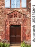 Old wooden entrance door to a red stone house in the village of Colonges la rouge in Corrèze in France
