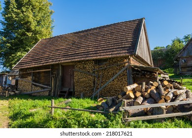 Old wooden farmhouse in the Carpathians with the wood in the yard.