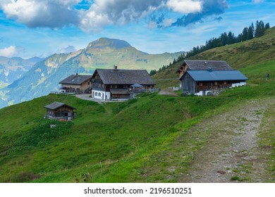 old wooden farmhouse on an alp with a view over the Grosse Walsertal, Vorarlberg. three-stage alpine agriculture in late summer, with lush green meadows on the steep mountains with forests and rocks. - Shutterstock ID 2196510251