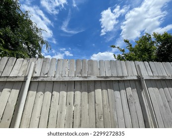 Old wooden fence in the backyard and flowing white clouds with blue sky and a corner of green trees, family lifestyle.