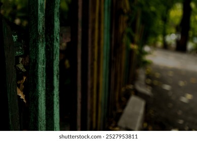 An old wooden fence with weathered green paint, partially covered by ivy leaves, leading into a serene pathway. The image captures the rustic charm and natural beauty of the fence set in an outdoor  - Powered by Shutterstock