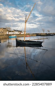 Old wooden fishing boat named Galway hooker reflected in water at Claddagh in Galway city, Ireland 