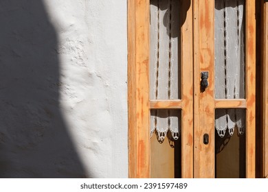 old wooden greek aegean or mediterranean window yeallow painted  with handmade white curtains