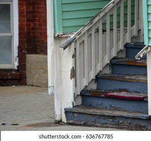 Old Wooden House Steps With Blue Peeling Paint In Urban Neighborhood Against A Brick Background 