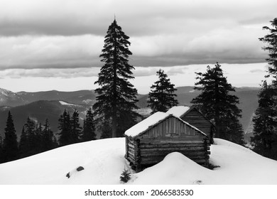 Old wooden hut in winter snowy mountains at gray day. Ukraine, Carpathian Mountains. Remote location. Black and white toned landscape.