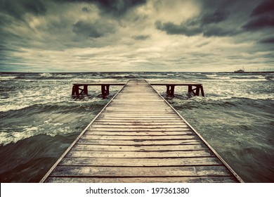 Old wooden jetty, pier, during storm on the sea. Dramatic sky with dark, heavy clouds. Vintage - Powered by Shutterstock