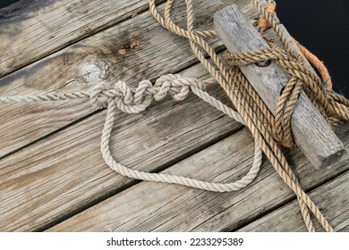 An old wooden jetty with ropes from boats attached to the mooring point,