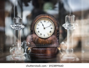 Old wooden mechanical wind up clock standing in antique shop window with reflections shining on glass telling time eleventh minute to passers by. Time showing 11:11 hours eleven minutes past eleven