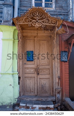 An old wooden peeling door with a mailbox in a rickety house